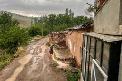 Abim Cuma, bir vakitler içinden balıkların geçtiği evin önündeki harka (toprak kanal) dolan suyu geçiyor. Yağmur sonrasında bu alanlara doluşan kurbağalar evin içine girmemeleri için çalı süpürgeleriyle uzaklaştırılırdı. Toprak kanal, 1980’li yıllara kadar köyiçinden geçer, yaklaşık yedi kilometre boyunca bahçelerin, bostanların, yoncalıkların ve hayvanların su ihtiyacını karşılardı. 2018 yılında bu evin bitişiğine iki katlı betonarme bir ev yapıldı. Abim Cuma emekli olduktan sonra köye yerleşti.
